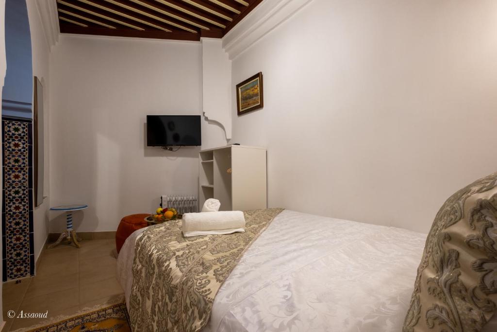une chambre avec un lit et une télévision au mur dans l'établissement Riad Bin Souaki, à Chefchaouen