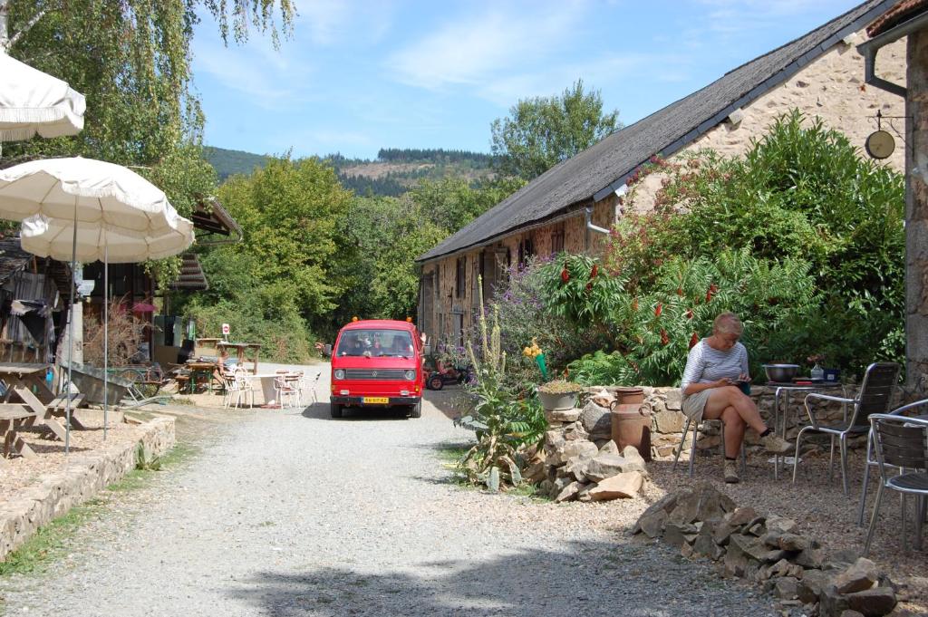 Une camionnette rouge circulant sur une route à côté d'un bâtiment dans l'établissement Camping La Forêt du Morvan, à Larochemillay