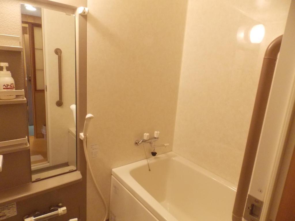 une salle de bain avec une baignoire et un lavabo dans l'établissement Ryokan Fushioukaku, à Ikeda