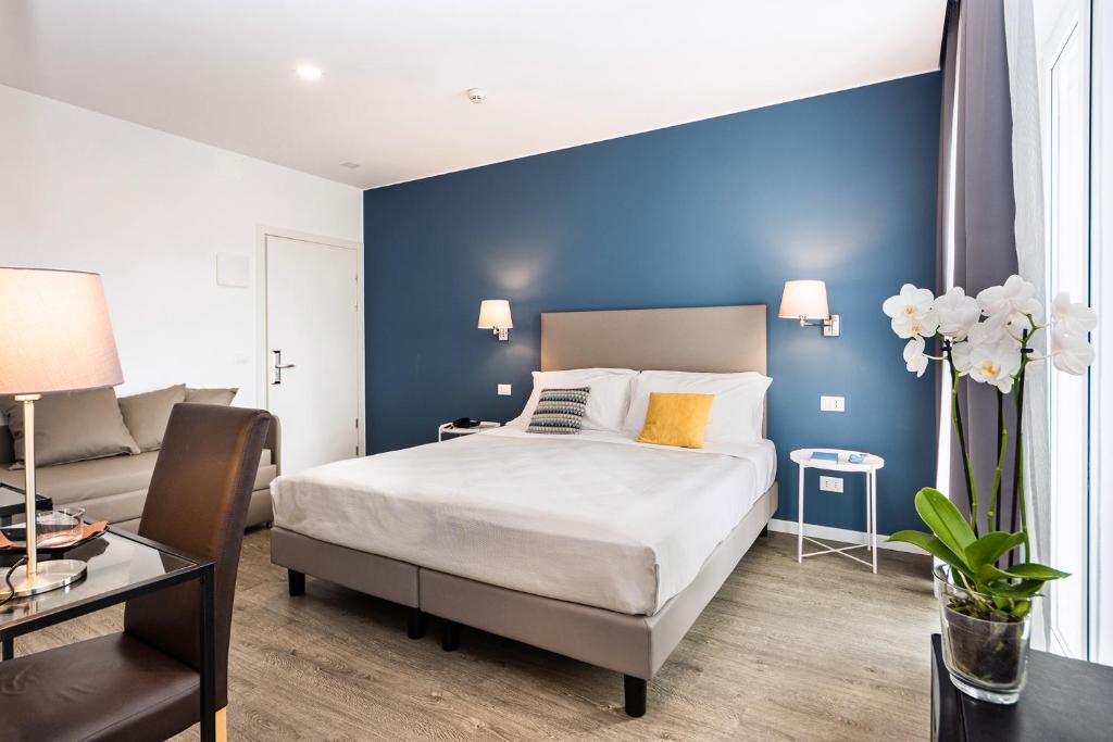une chambre avec un lit et un mur bleu dans l'établissement Hotel Aurora, à Lignano Sabbiadoro