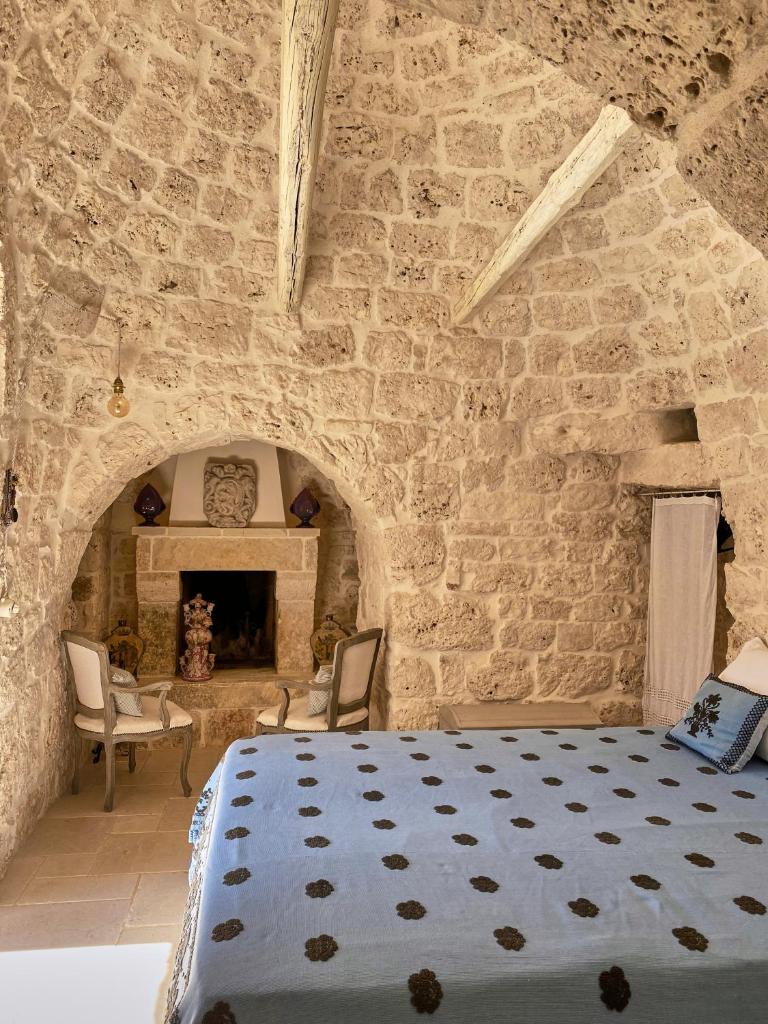 - une chambre aux murs en pierre avec un lit et une cheminée dans l'établissement TRULLO SILENTIO, Ostuni - w private pool, à Ostuni