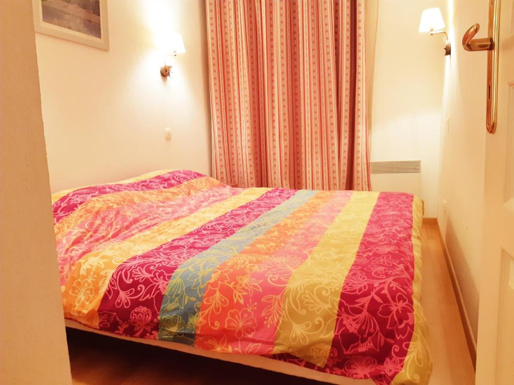 une chambre avec un lit avec une couette colorée dans l'établissement Le Marmotton, T2, centre Luchon, wifi, casier à skis, ascenseur, 5 personnes, à Luchon