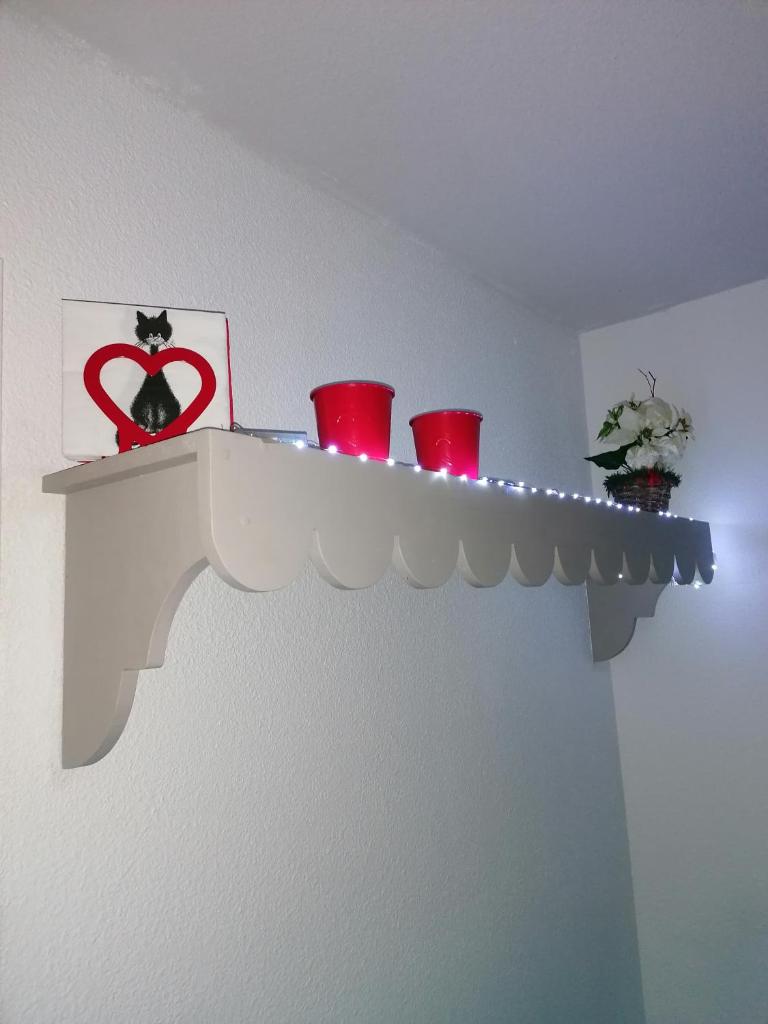 une étagère avec des tasses rouges et une image de cœur dans l'établissement CŒUR D'ALTAÏR RISOUL 1850 Appartement T2 confortable skis aux pieds, à Risoul