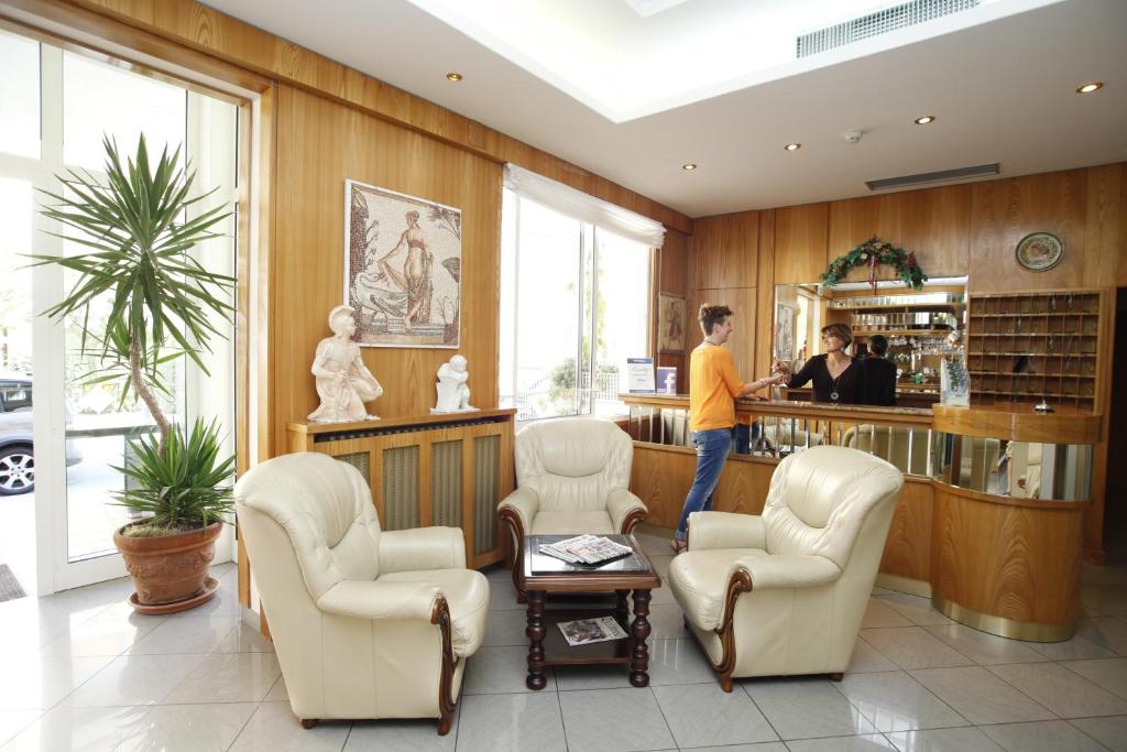 une femme debout au comptoir dans une salle d'attente dans l'établissement Hotel Villa dei Fiori - sul mare con piscina, à Rimini 103 autres photos