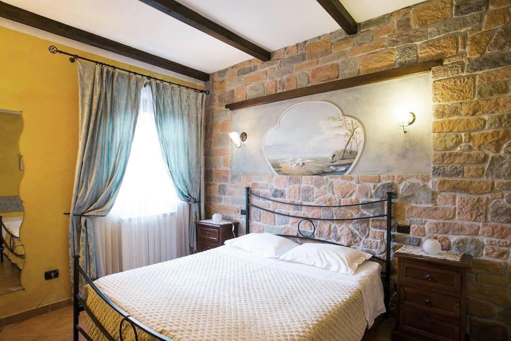 une chambre avec un lit et un mur de briques dans l'établissement Agriturismo dal nonno Merico, à Corfino