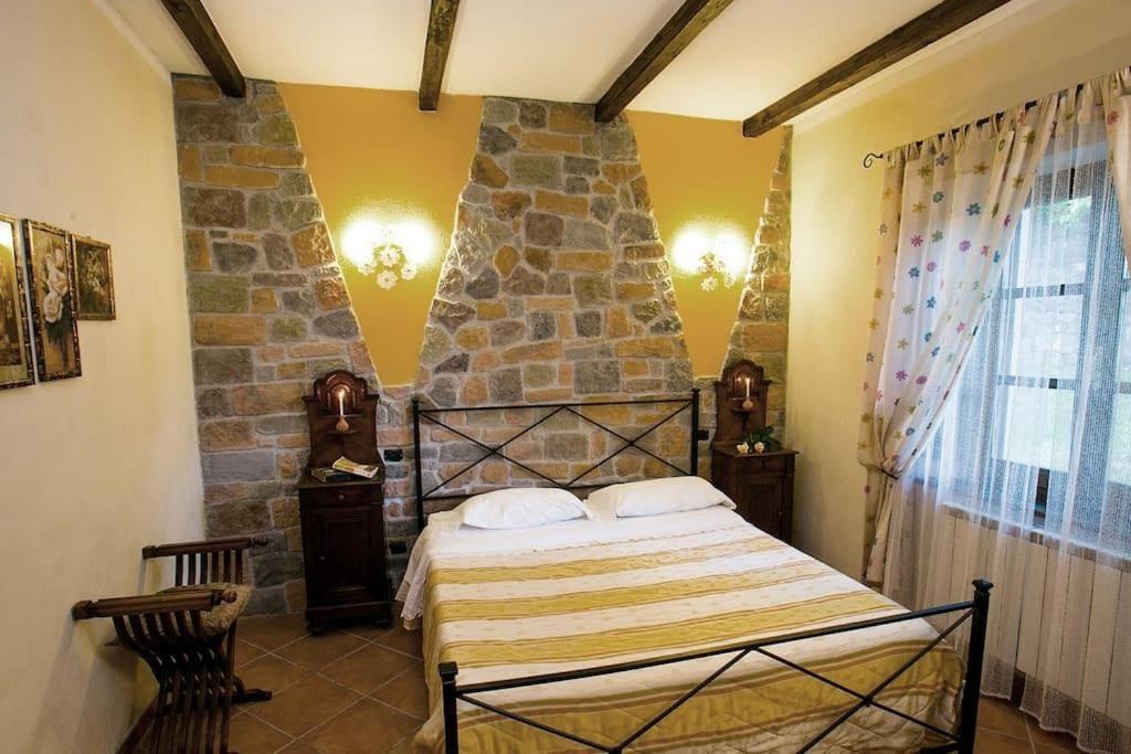 une chambre avec un lit et un mur en pierre dans l'établissement Agriturismo dal nonno Merico, à Corfino