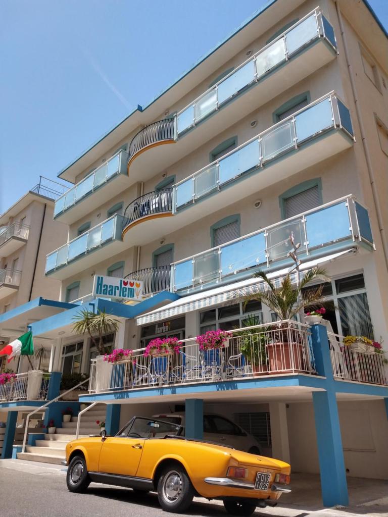 une vieille voiture jaune garée devant un bâtiment dans l'établissement Hotel Haarlem, à Rimini