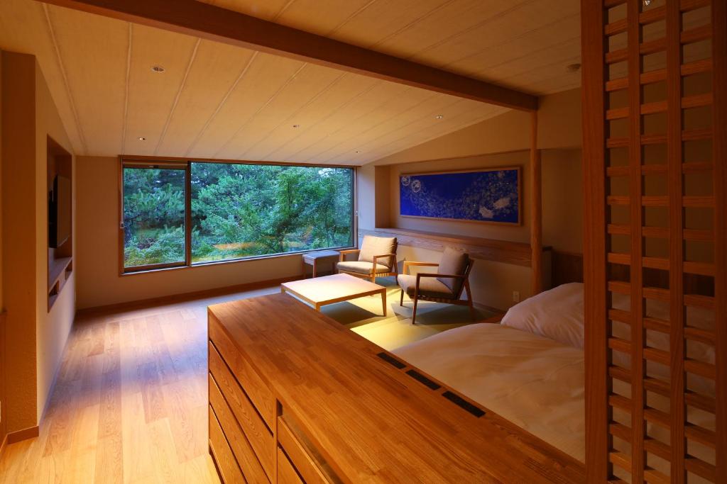 une chambre avec un grand lit et une grande fenêtre dans l'établissement Monjusou, à Miyazu