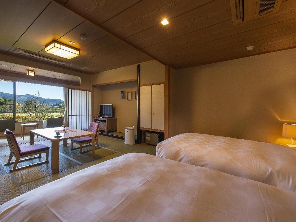 une chambre d'hôtel avec deux lits, une table et des chaises dans l'établissement Shimoda Central Hotel, à Shimoda