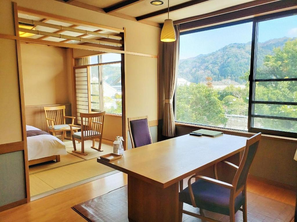 Cette chambre comprend un bureau, un lit et une grande fenêtre. dans l'établissement Saginoyusou, à Yasugi