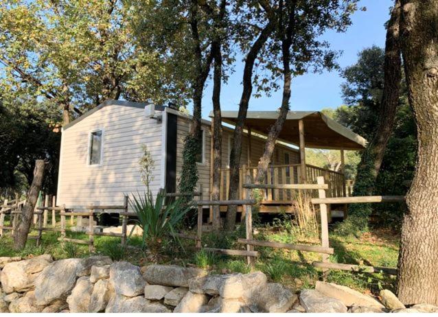 une petite maison avec une terrasse couverte dans les bois dans l'établissement Camping La Montagne, à Sorgues