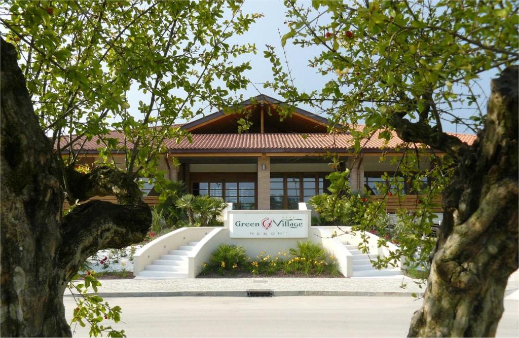 un bâtiment avec une enseigne devant lui dans l'établissement Green Village Eco Resort, à Lignano Sabbiadoro
