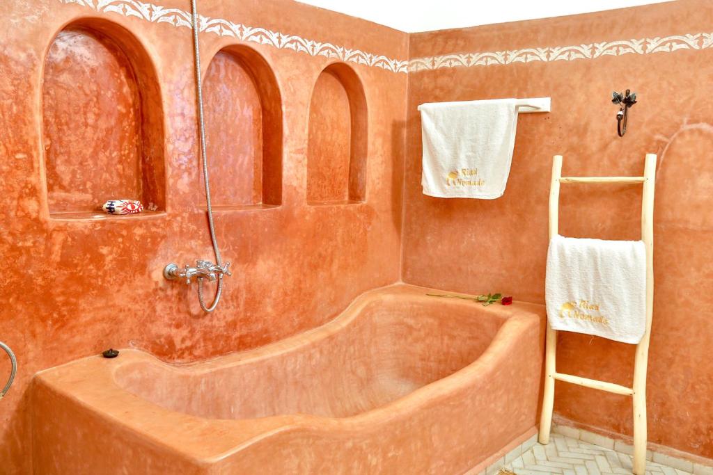 La salle de bains est pourvue d'une baignoire, d'une échelle et de serviettes. dans l'établissement RYAD DES NOMADES, à Essaouira