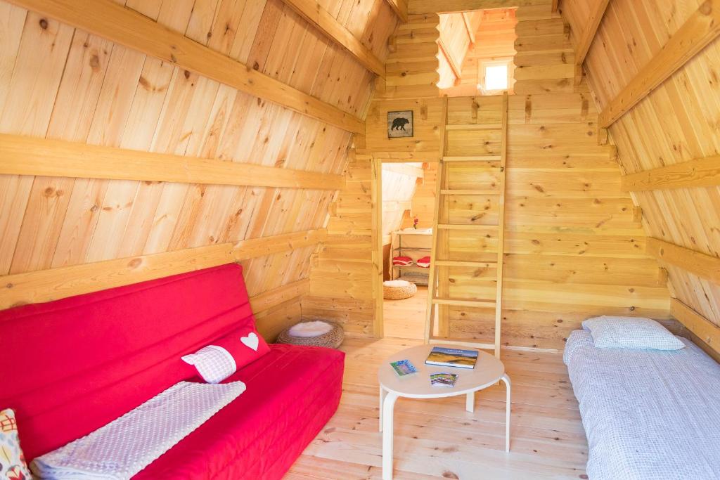 une chambre avec un canapé rouge dans une cabane en bois dans l'établissement Ferme Rony Camp des Découvreurs, à Saint-Nizier-du-Moucherotte