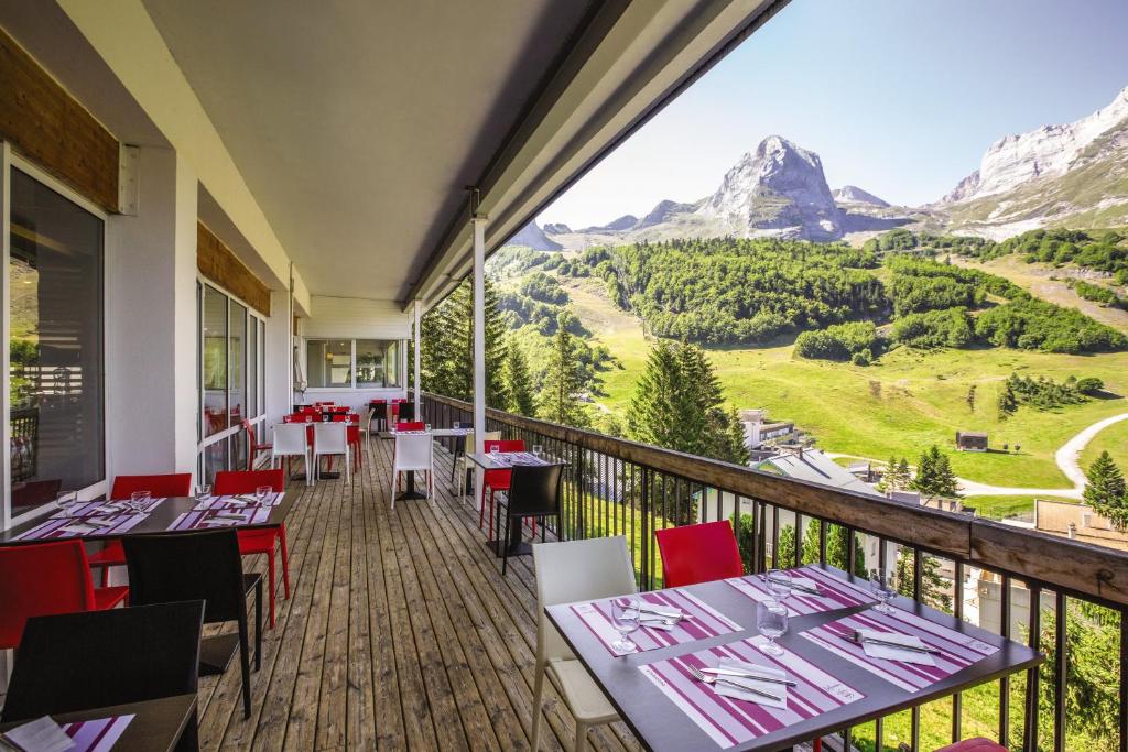 un restaurant avec des tables et des chaises sur un balcon avec des montagnes dans l'établissement Belambra Clubs Gourette - Lou Sarri, à Gourette