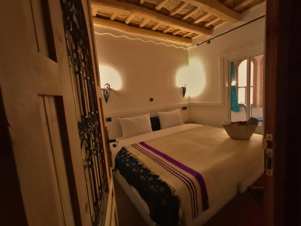 une chambre avec un lit dans une pièce avec une fenêtre dans l'établissement Riad Bleu Afriqua, à Boumalne