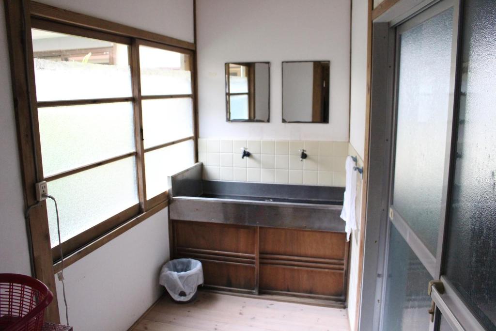une salle de bain avec un lavabo et un miroir dans l'établissement Minshuku Katsuya, à Shirahama 11 autres photos