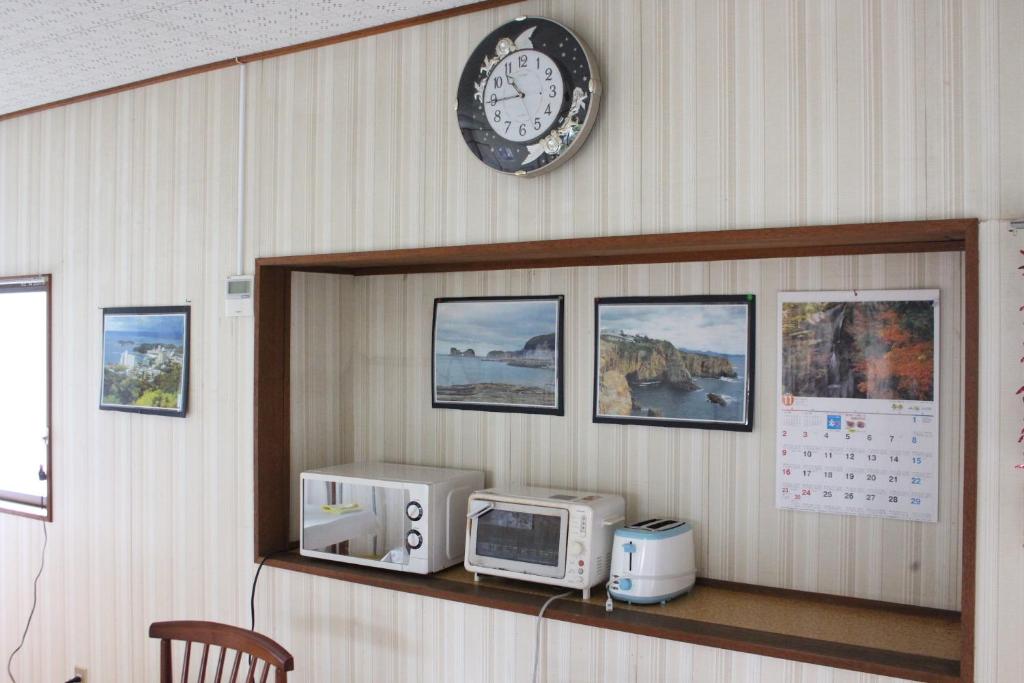 une horloge sur un mur au-dessus d'un comptoir avec un four micro-ondes dans l'établissement Minshuku Katsuya, à Shirahama