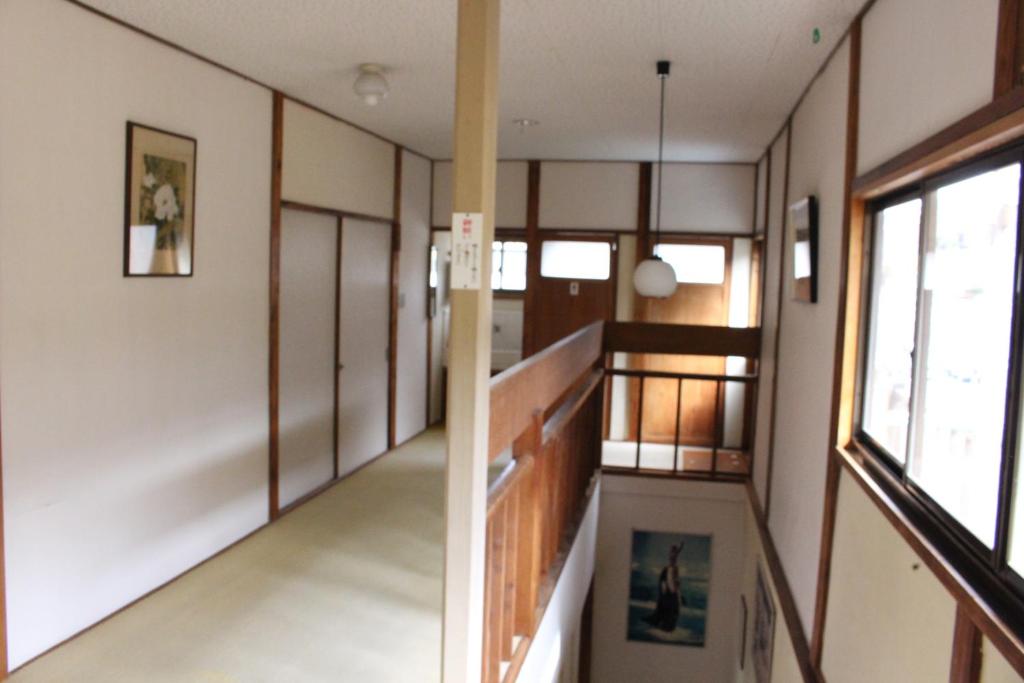 un couloir d'une maison avec un escalier et des fenêtres dans l'établissement Minshuku Katsuya, à Shirahama