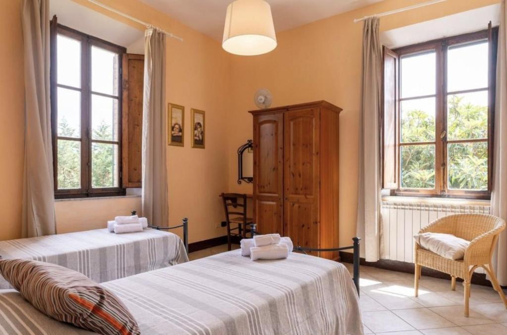 deux lits dans une chambre avec deux fenêtres dans l'établissement Il Vecchio Mulino Toscana, à Radicondoli
