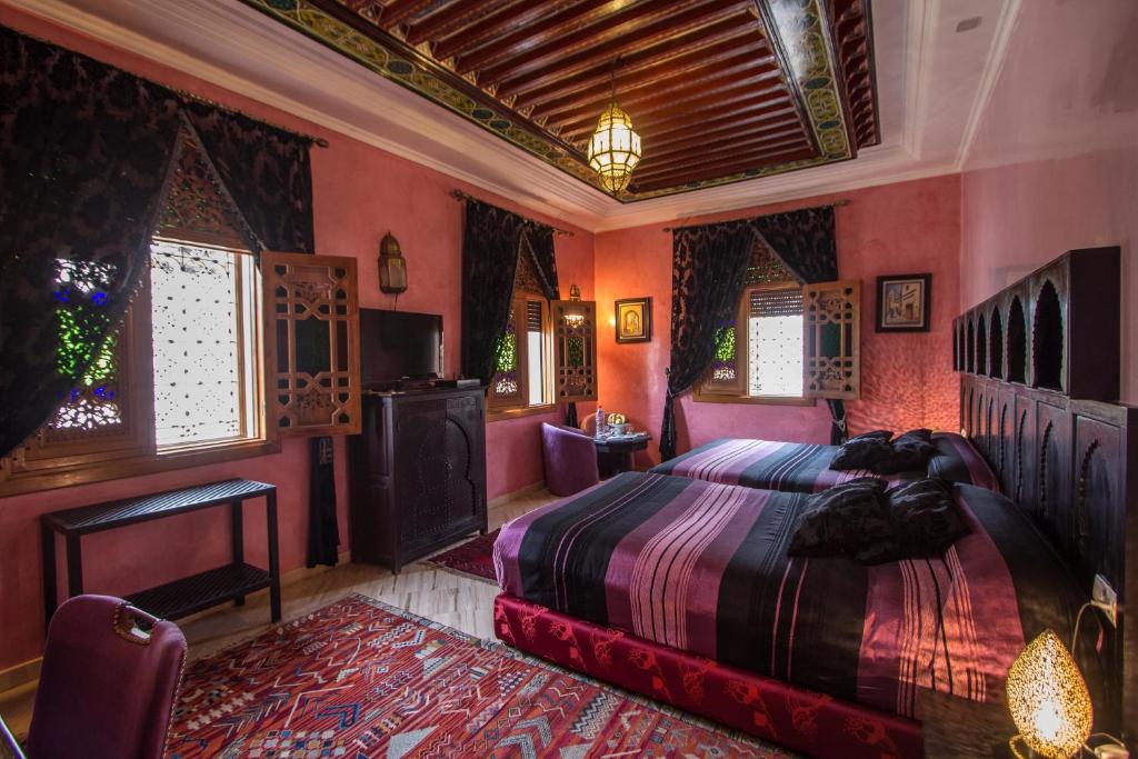 - une chambre avec un grand lit aux murs roses dans l'établissement Riad Raouia HAMMAM & SPA, à Fès