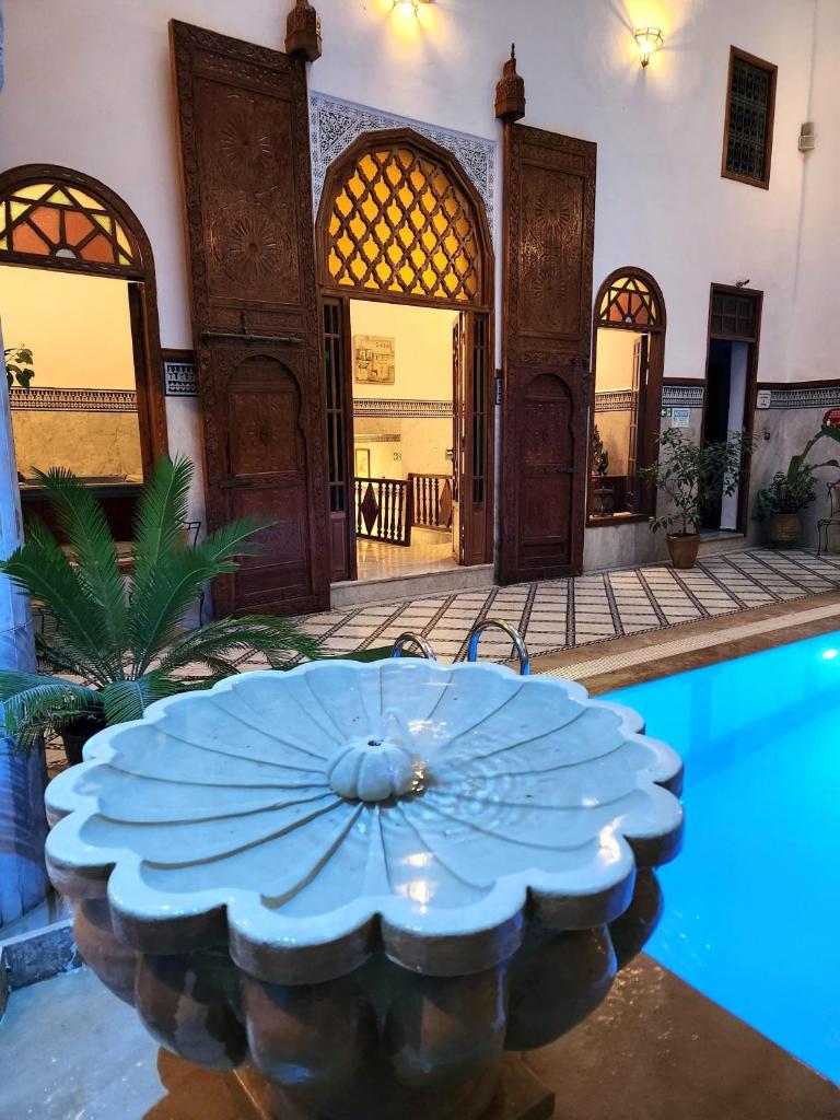 une maison avec une piscine dotée d'un parasol bleu dans l'établissement Le Riad Palais d'hotes Suites & Spa Fes, à Fès