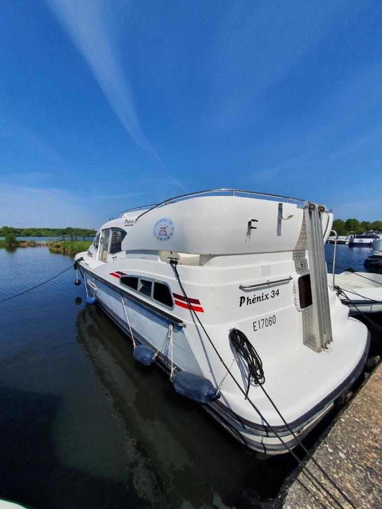 un bateau blanc amarré à un quai dans l'eau dans l'établissement Magnifique bateau au coeur du Nivernais à l'étang de BAYE, à Bazolles 8 autres photos