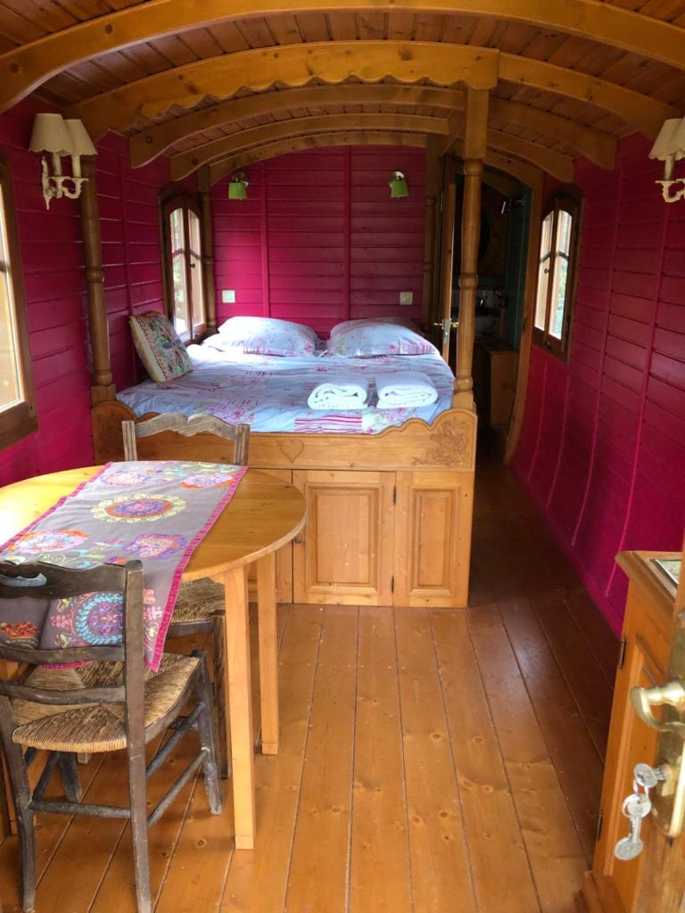 une chambre avec un lit et une table dans une pièce dans l'établissement ROULOTTE CAPUCINE, à Ablon
