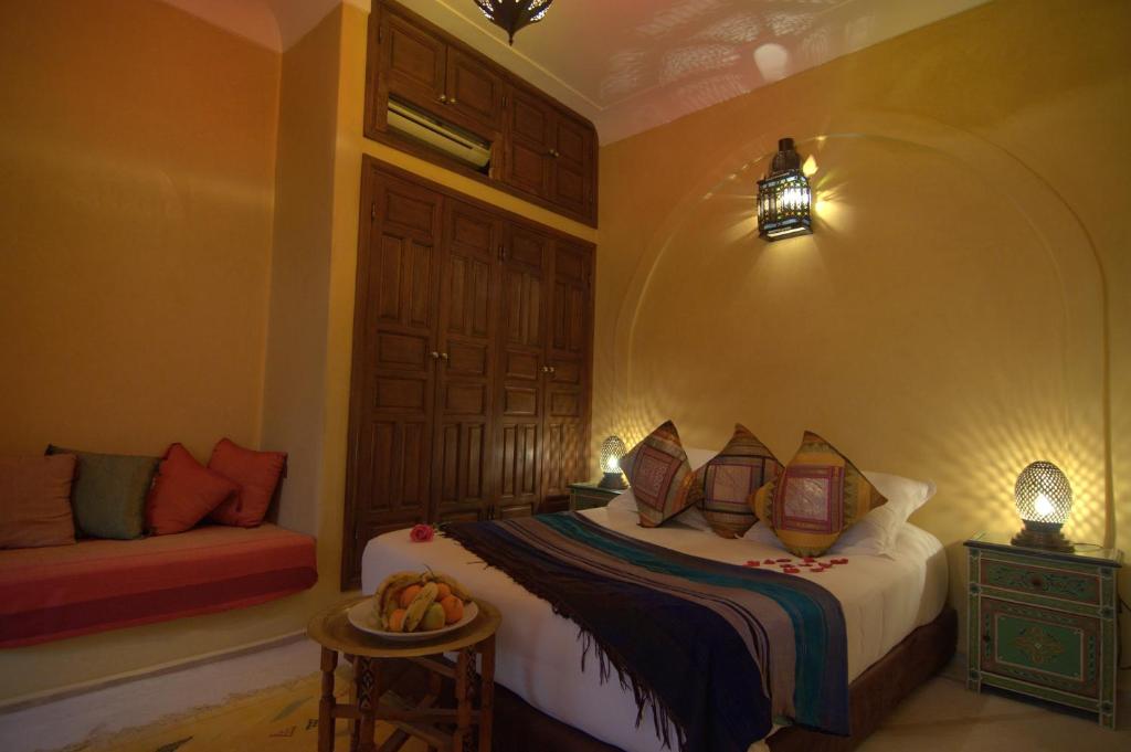 - une chambre avec un lit et un banc dans l'établissement Riad Imilchil, à Marrakech