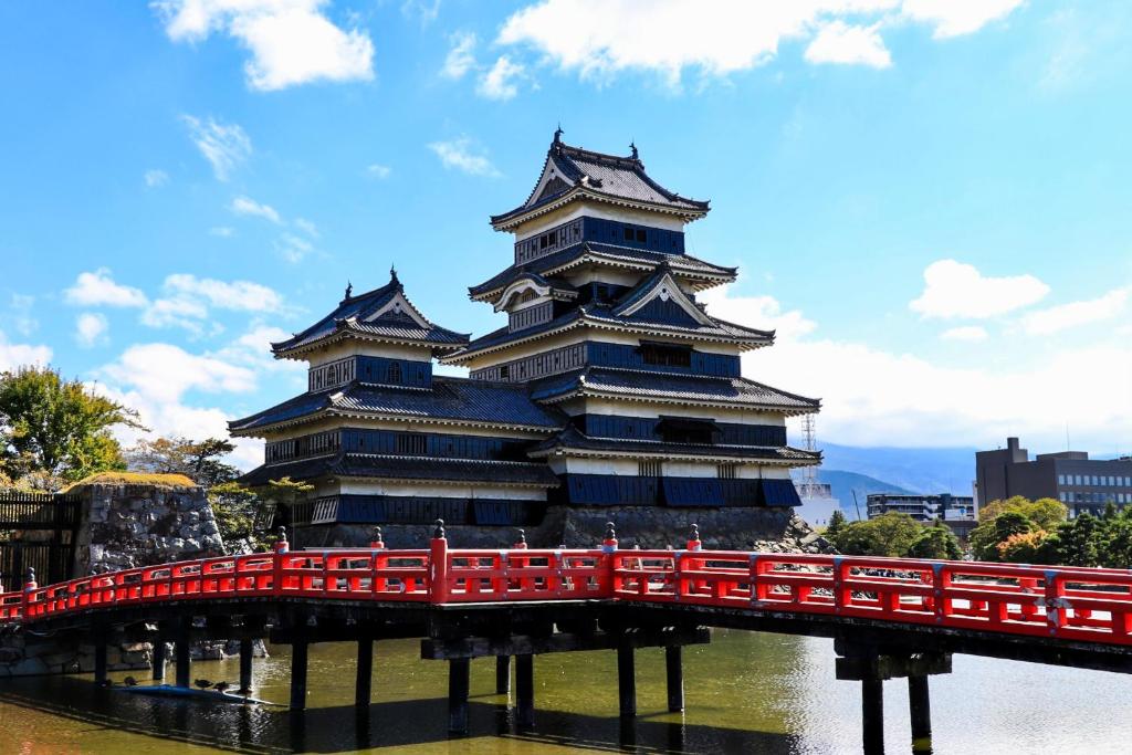 un grand bâtiment avec un pont rouge sur une rivière dans l'établissement Awanoyu, à Matsumoto