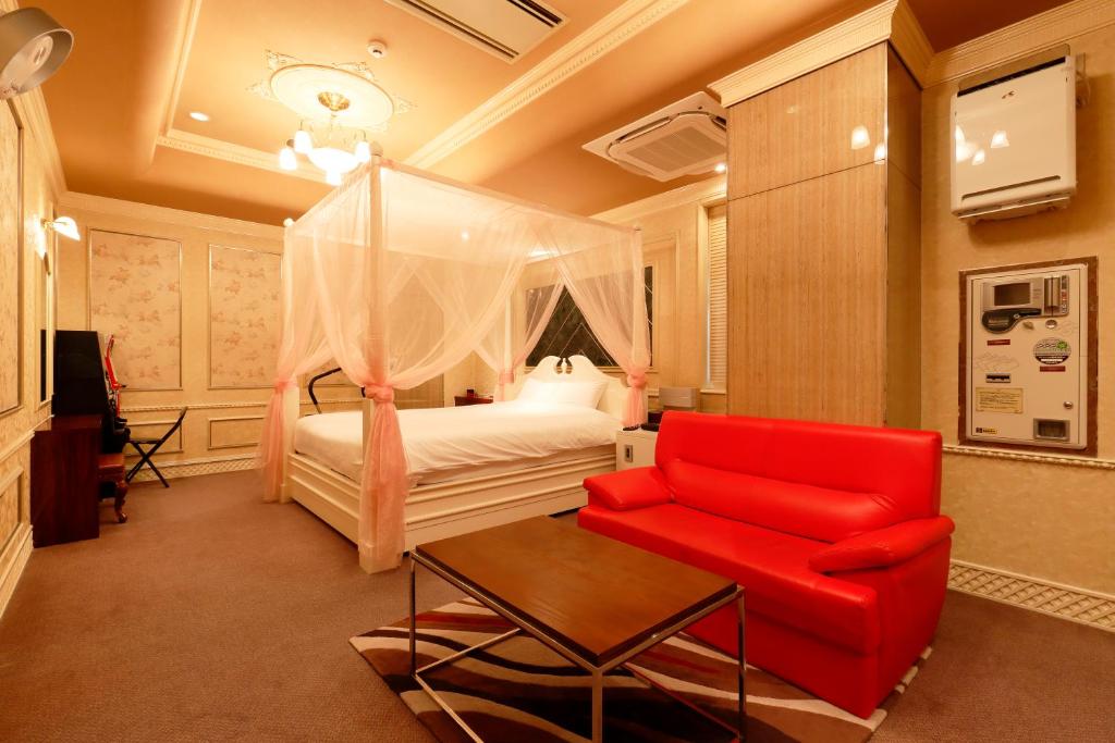 une chambre avec un lit et une chaise rouge dans l'établissement HOTEL555 伊豆長岡, à Izunokuni