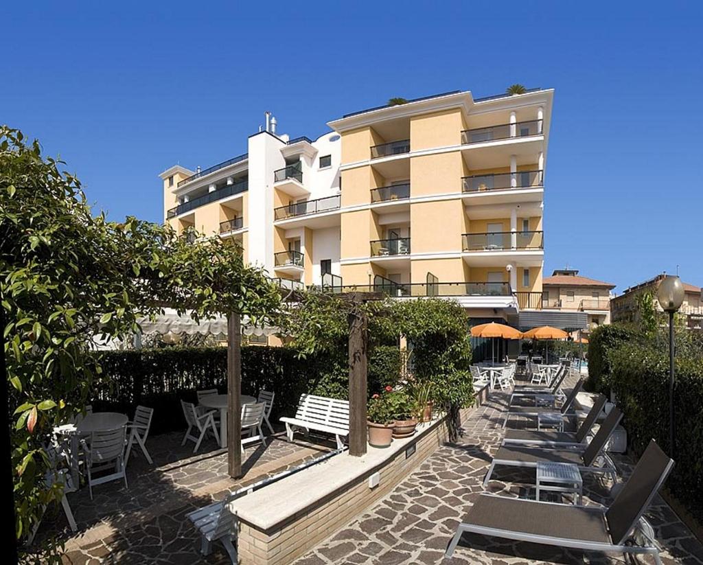 un bâtiment avec des chaises et des tables devant un bâtiment dans l'établissement Hotel Imperial, à San Benedetto del Tronto