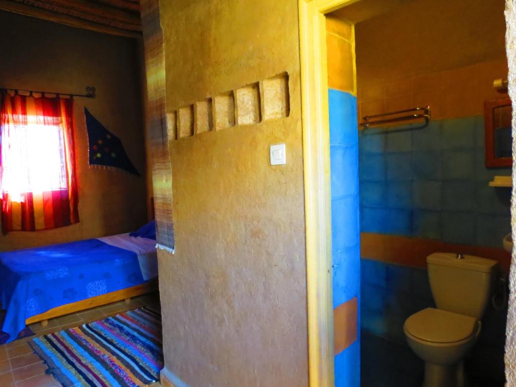 - une salle de bains avec toilettes et un lit dans une chambre dans l'établissement Hôtel Riad Tadarte Familier, à Merzouga