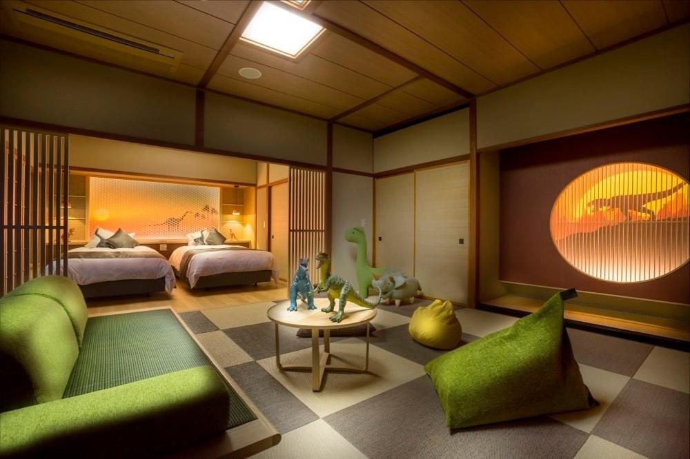 - une chambre avec 2 lits, une table et un mobilier vert dans l'établissement Grandia Housen, à Awara
