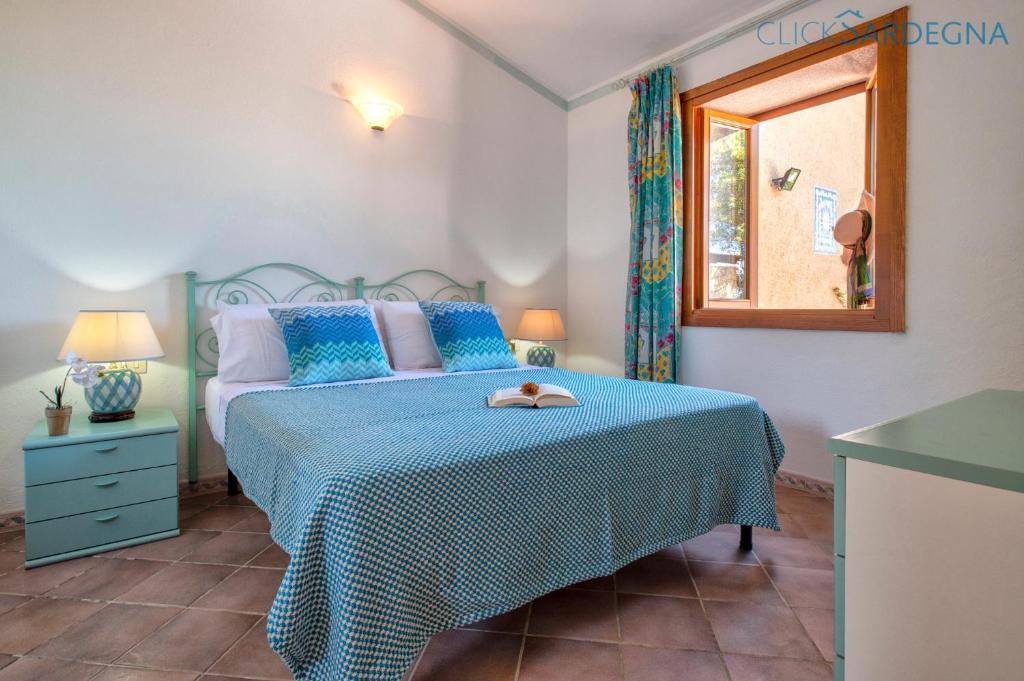 une chambre avec un lit avec une couette bleue et une fenêtre dans l'établissement Costa Paradiso villa con piscina indipendente e vista mare per 6 persone, à Costa Paradiso