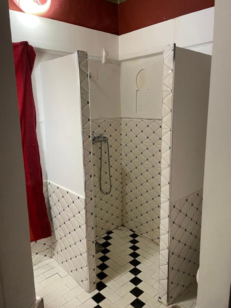 une douche avec une porte vitrée dans une salle de bain dans l'établissement Riad Bleu Afriqua, à Boumalne