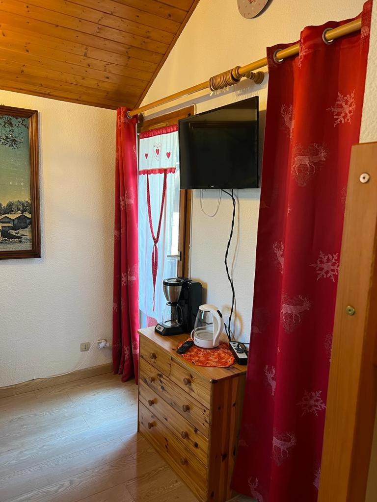 Cette chambre dispose de rideaux rouges et d'une commode avec télévision. dans l'établissement Appartement MANA, à Bernex