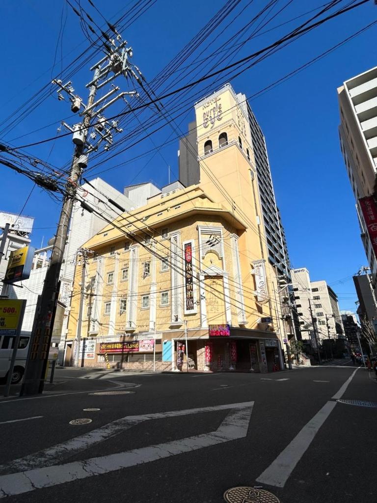 un grand bâtiment jaune au coin d'une rue dans l'établissement hotel purpleeye, à Osaka