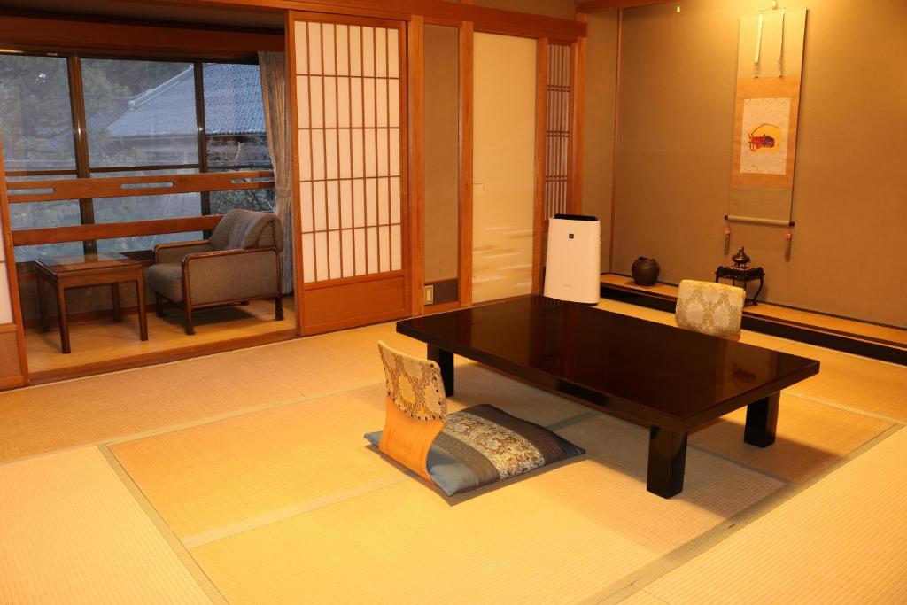 un salon avec une table et des chaises noires dans l'établissement Tsutaya Ryokan, à Toyooka
