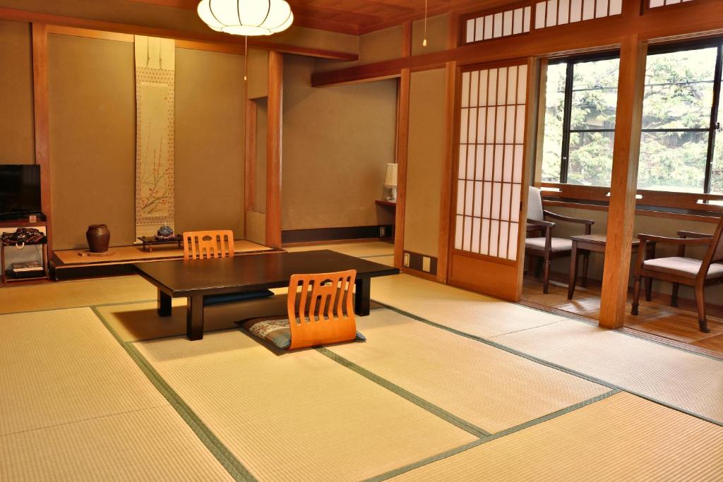 une pièce avec une table et des chaises et une salle à manger dans l'établissement Tsutaya Ryokan, à Toyooka