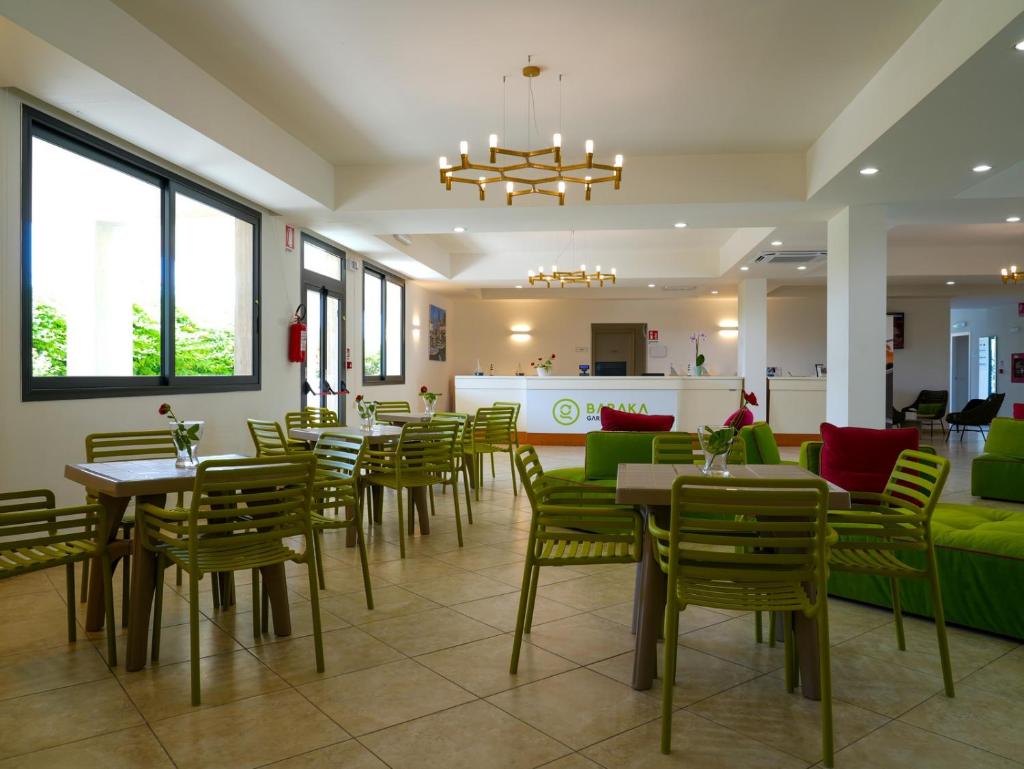 une salle à manger avec des tables et des chaises vertes dans l'établissement GH Baraka Village, à Scoglitti