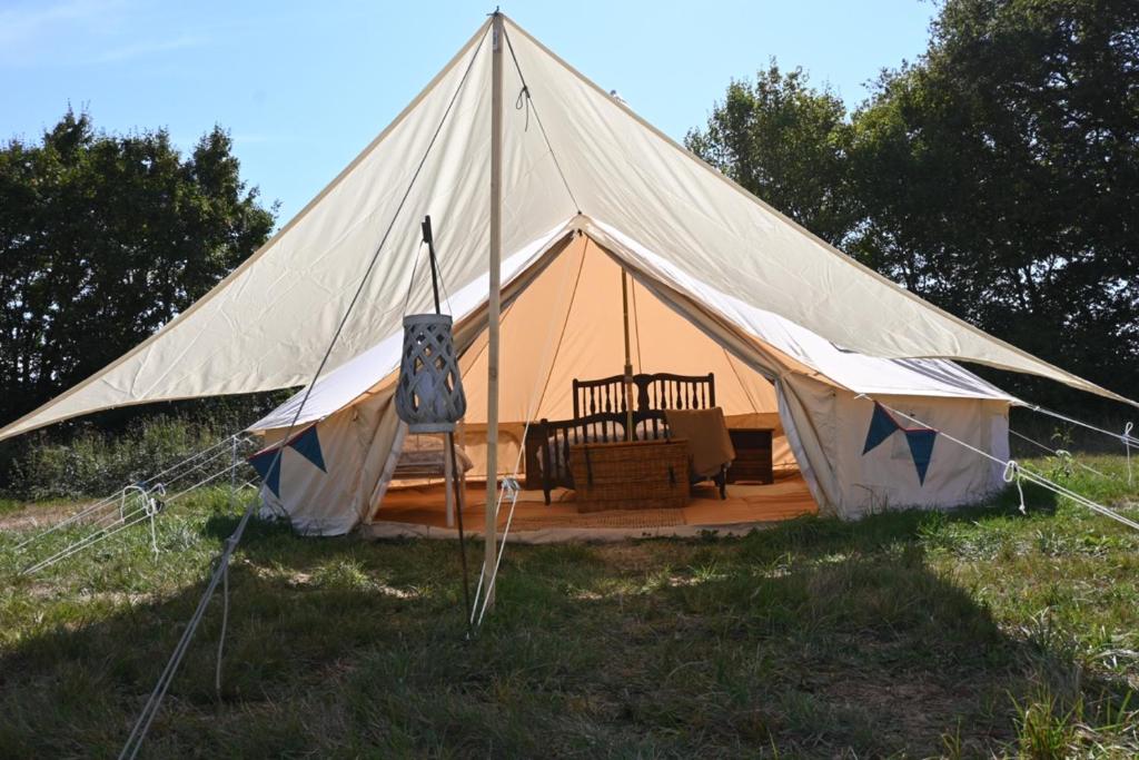 une grande tente avec une chaise dans un champ dans l'établissement Chateau Morinerie Glamping, à Villiers 14 autres photos