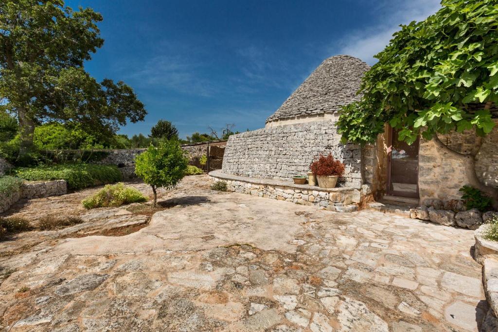 - une vue extérieure sur une maison en pierre avec un jardin dans l'établissement Trulli di Monte Reale by Perle di Puglia, à Cisternino