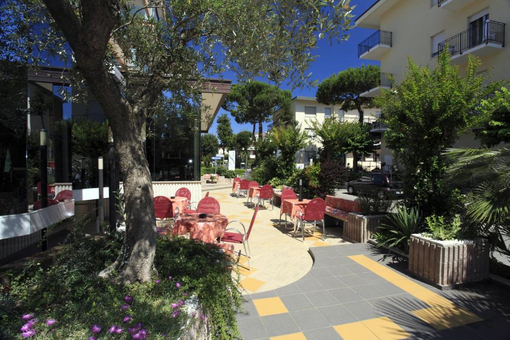un patio avec des tables et des chaises et un arbre dans l'établissement Hotel Conti, à Rimini
