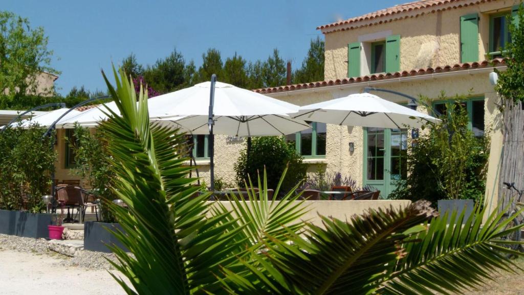 une maison avec deux parasols blancs devant elle dans l'établissement Camping Tikayan Félix de la Bastide, à Saint-Mitre-les-Remparts