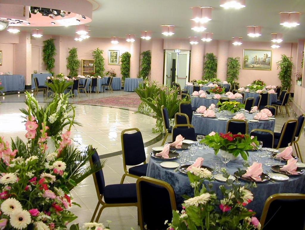 une salle de banquet avec des tables bleues, des chaises et des fleurs dans l'établissement Hotel Villa, à Bisceglie 79 autres photos