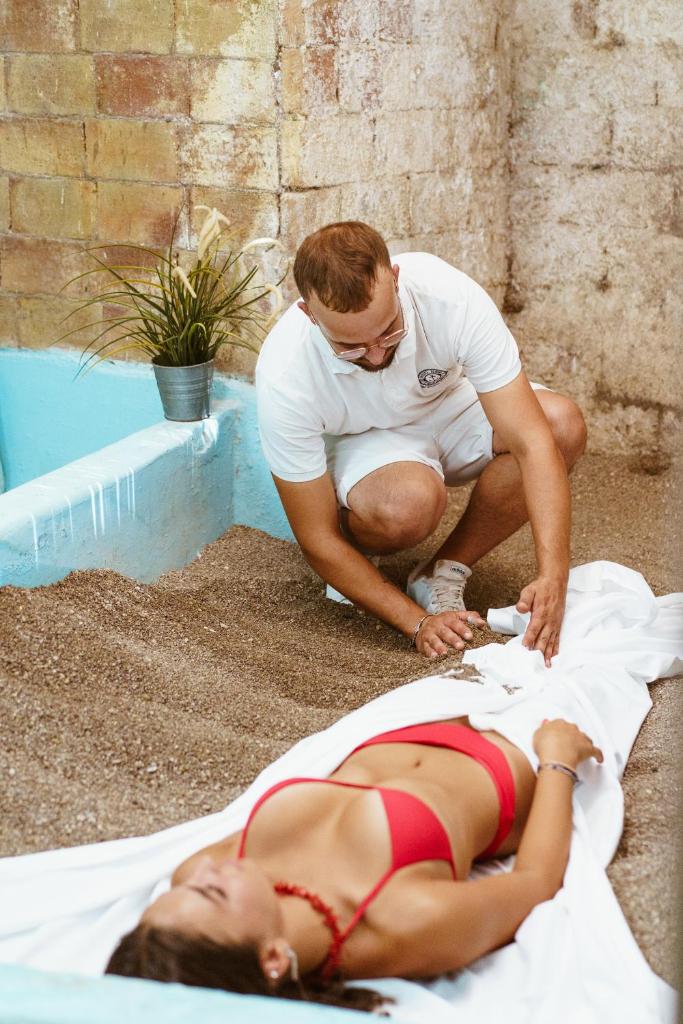 un homme assis à côté d'une femme assise sur le sol dans l'établissement Hotel Ferdinando Beach & Thermal Spa, à Ischia