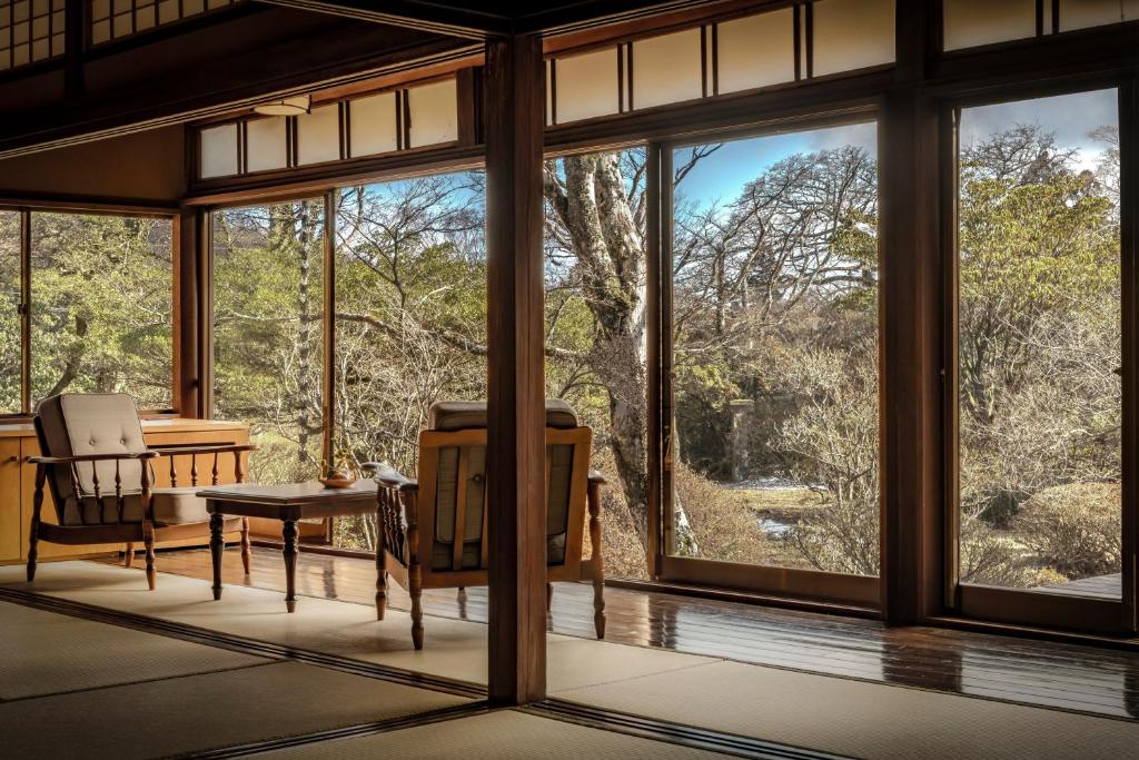 Cette chambre dispose de grandes fenêtres, d'une table et de chaises. dans l'établissement Matsuzakaya Honten, à Hakone