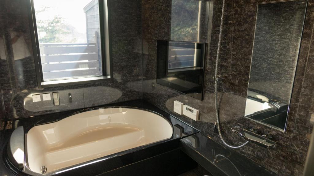 une baignoire dans une salle de bain avec une fenêtre dans l'établissement Mayu Futahari, à Nishiizu
