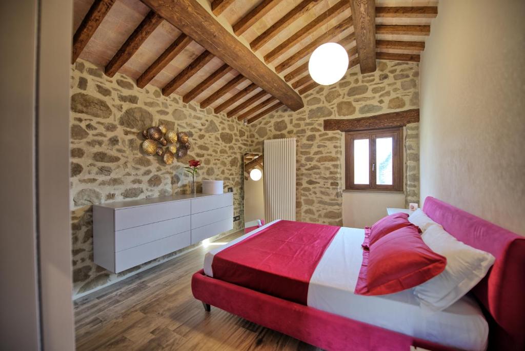 - une chambre avec un lit rouge et blanc et un mur en pierre dans l'établissement Villa Mulino by PosarelliVillas, à Poggioni